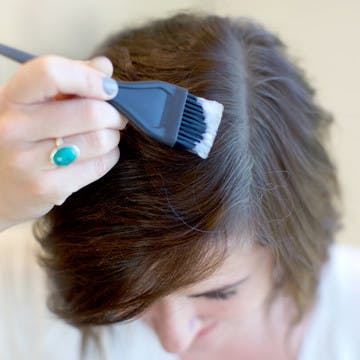 Image closeup of woman dying her graying roots with eSalon's custom home hair color