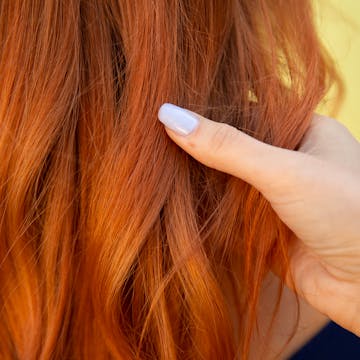 Model's hand sweeps through her vibrant copper red hair.