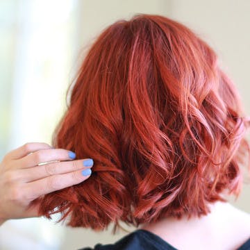 Woman with esalon's custom red hair color looking in mirror