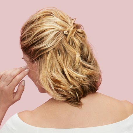 Image of esalon client victoria's back of head with blonde hair and highlights in a half-up-half-down easy updo with beautiful gold pins to hold hair as hero image in how to article featured on color mastery