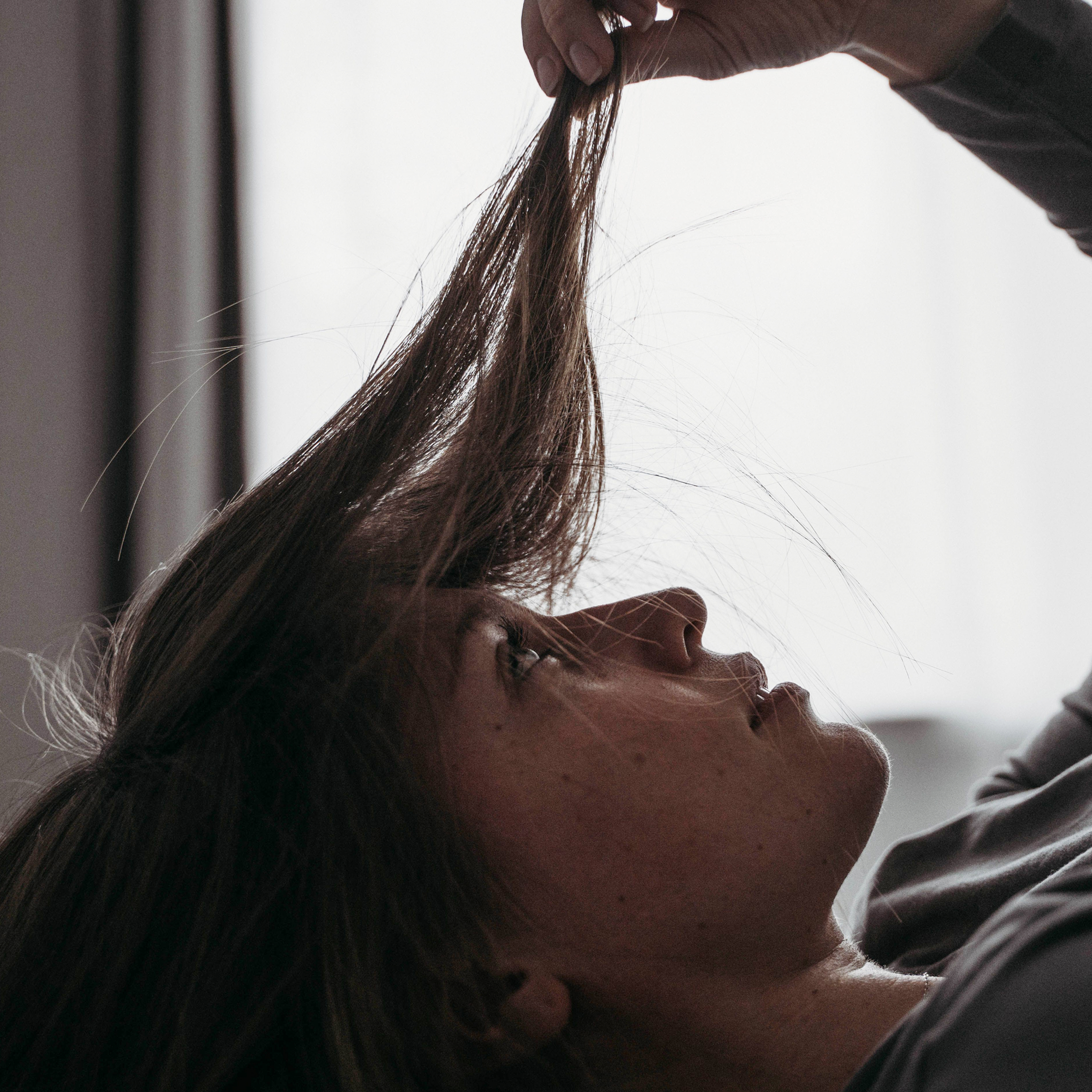 Woman closely examining her hair. 