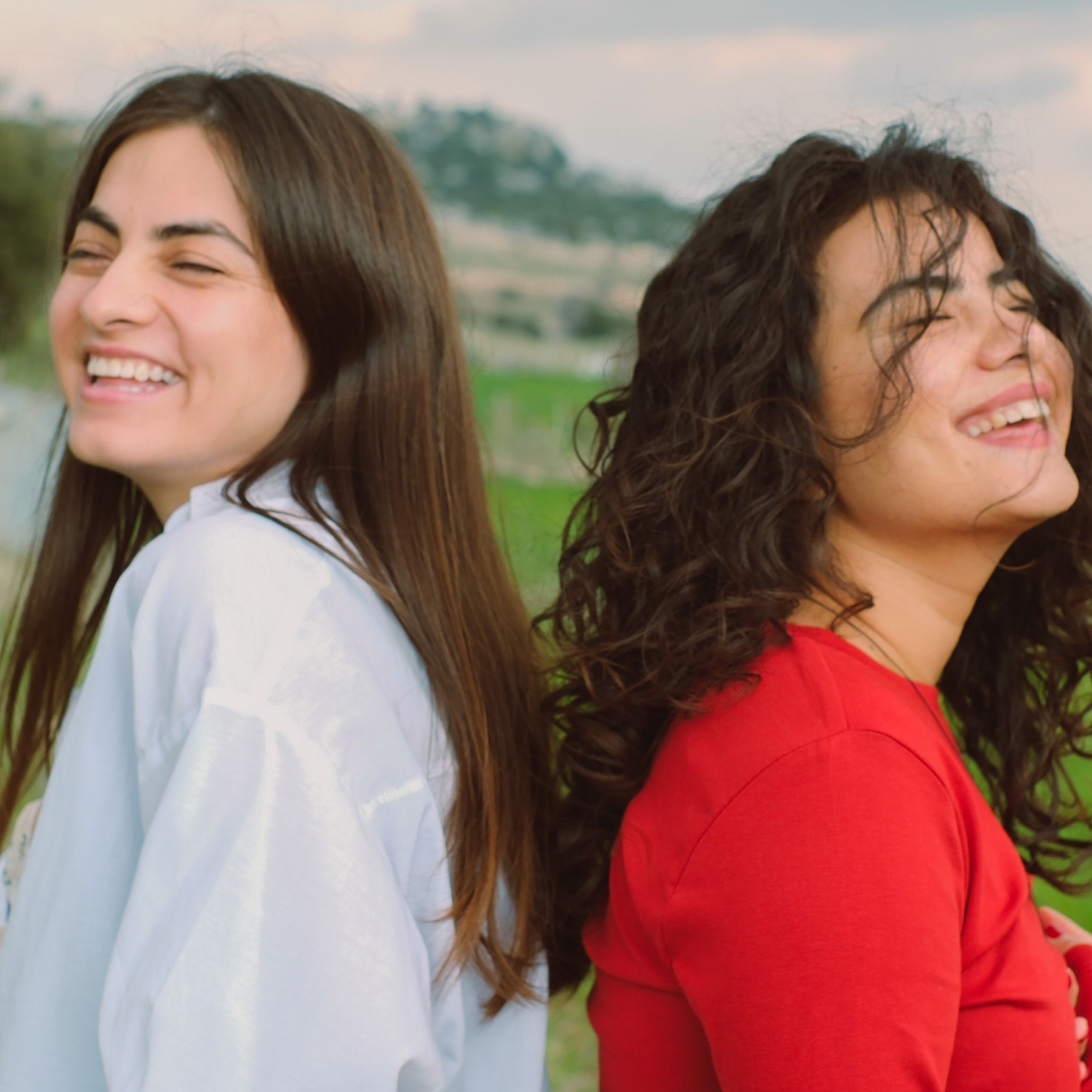 Two women next to each other with different hair types smiling.
