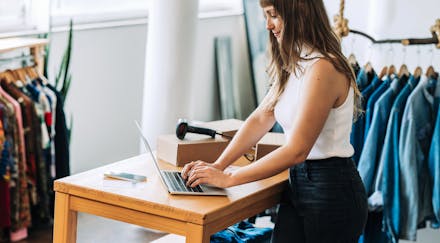 Young clothing store owner using a laptop in her shop