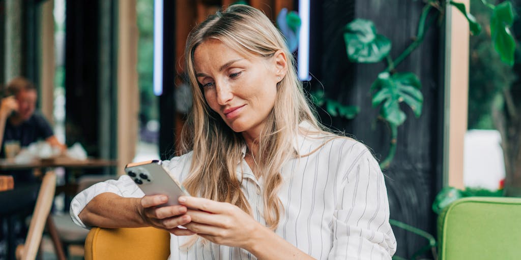 A woman uses a mobile phone to communicate while sitting in a coffee house.