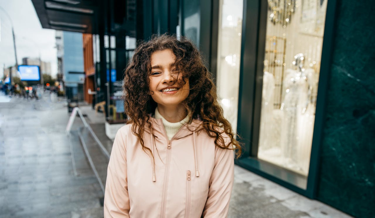 A woman smiles at the camera on a rainy day on a city street