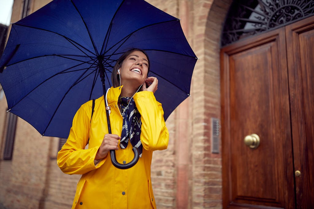 Woman in a yellow raincoat, under blue umbrella