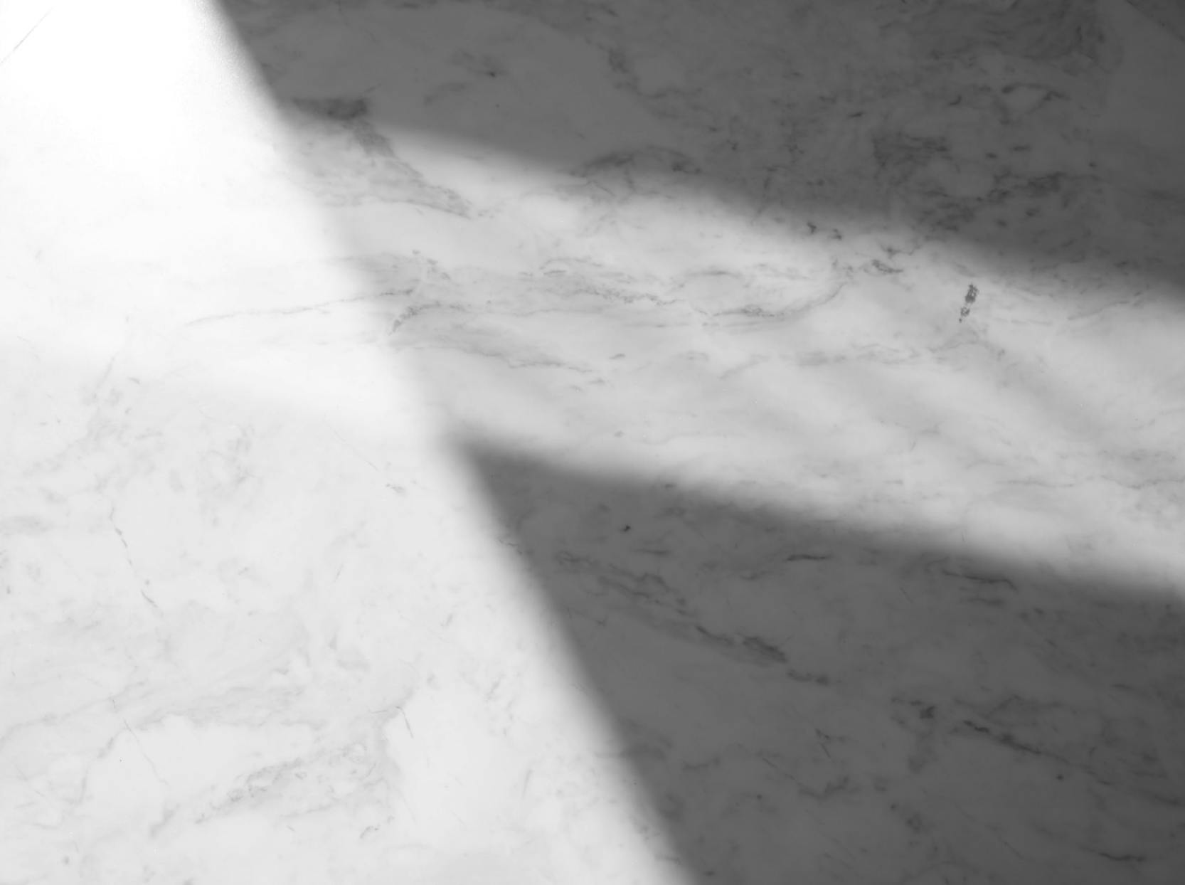 Marble surface with diagonal shadow falling across it.
