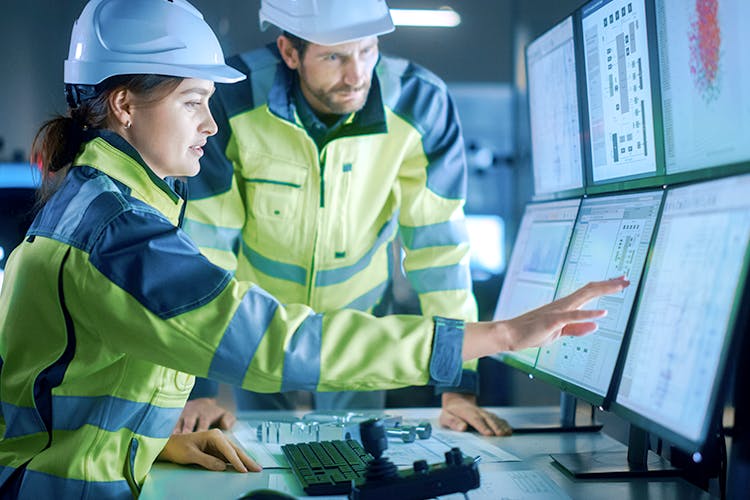 Image of female & male workers looking at 6 screens of information
