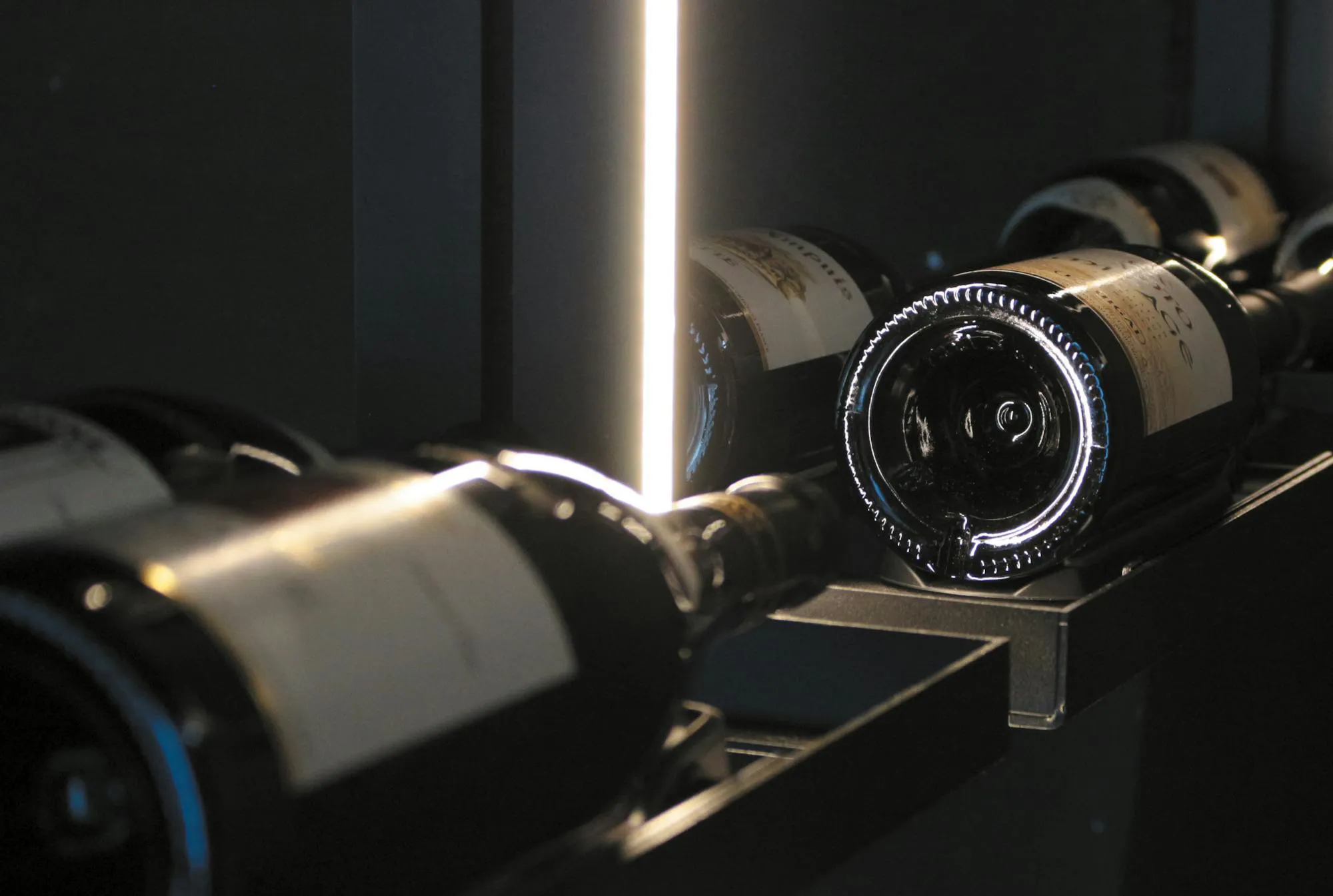Détail d'une cave à vin EuroCave Modulo X : des bouteilles couchées, éclairées par une fine ligne lumineuse.