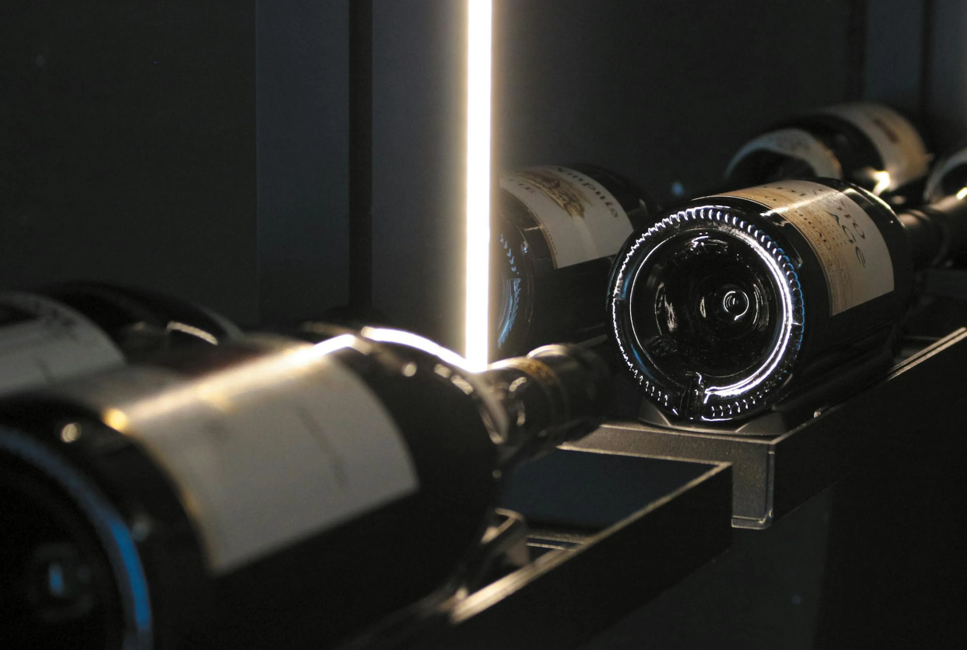 Close-up of a EuroCave Modulo X wine cellar: bottles resting on the racking, lit by a slim light strip.