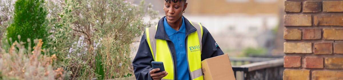 female courier holding parcel and smartphone outside 