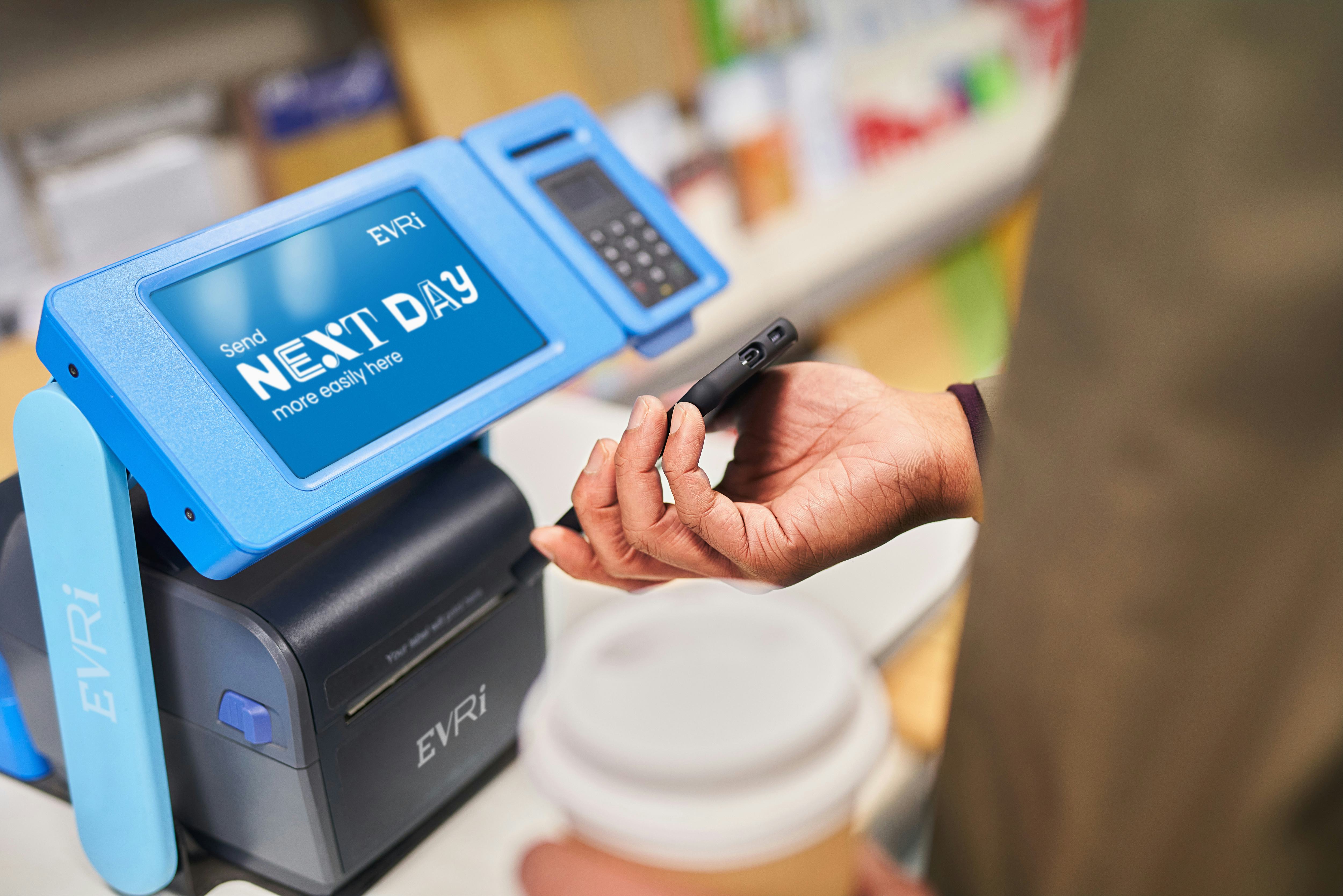 Photo of a customer holding smartphone to blue parcelshop terminal