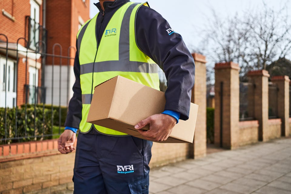 Photo of a courier holding parcel and walking down street