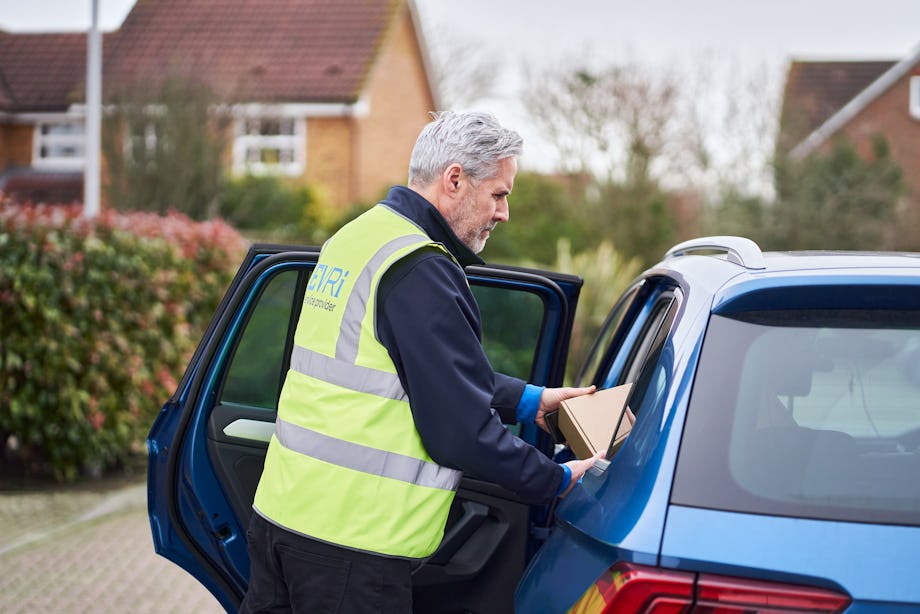 courier opening door of blue car to place package inside