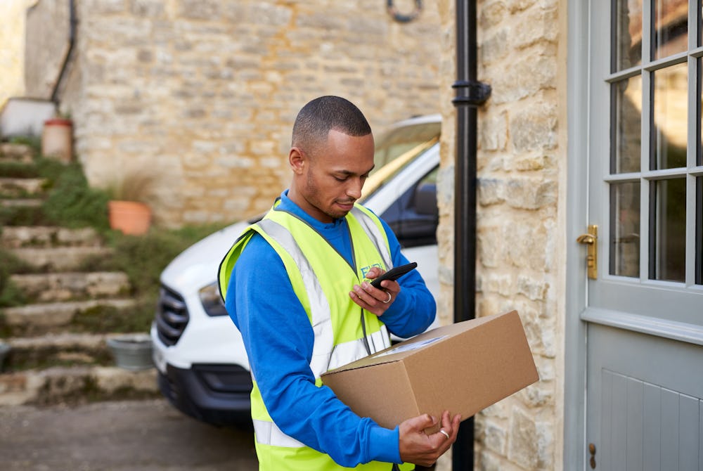 Photo of a courier on doorstep scanning box with smartphone