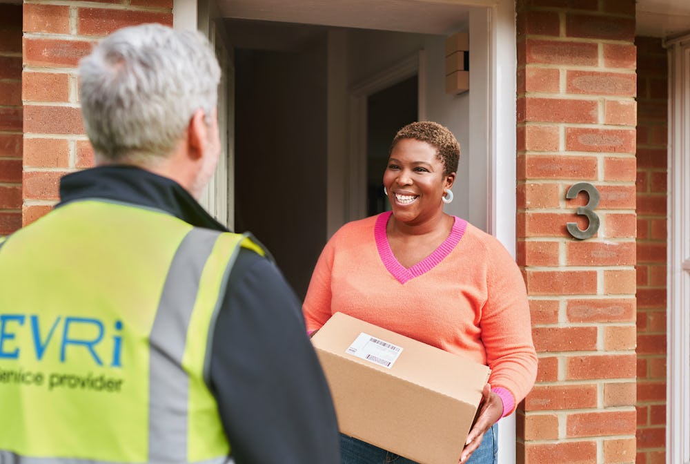 woman on doorstep holding box and talking to male courier