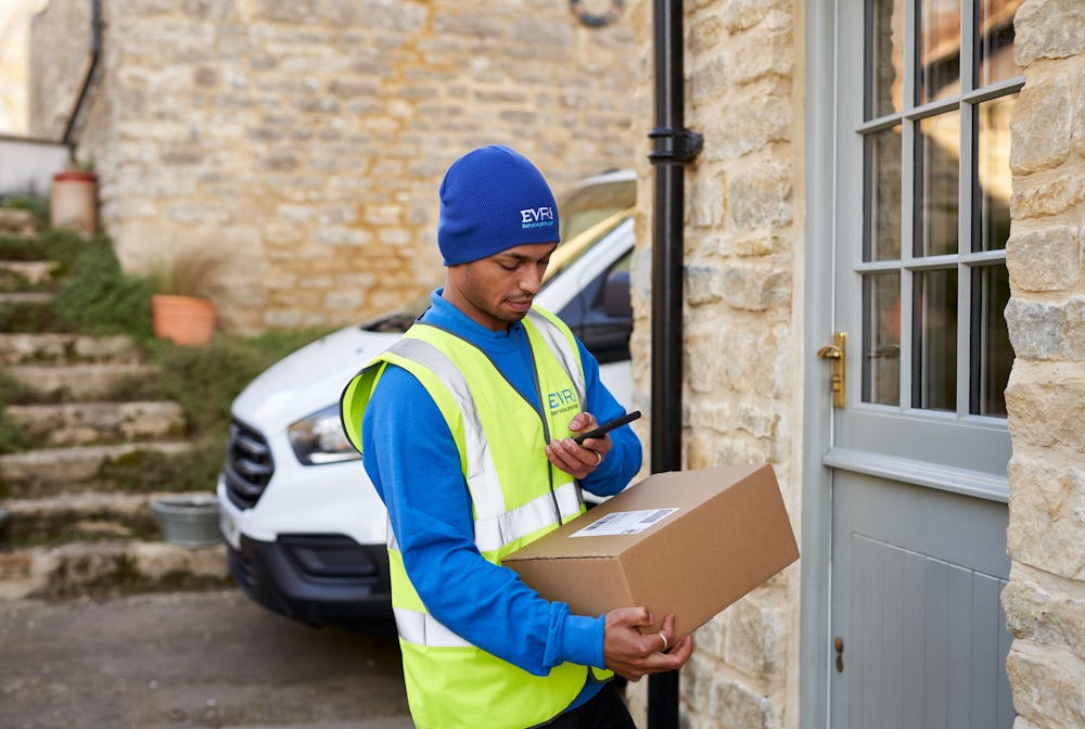 courier holding parcel on doorstep and scanning on smartphone