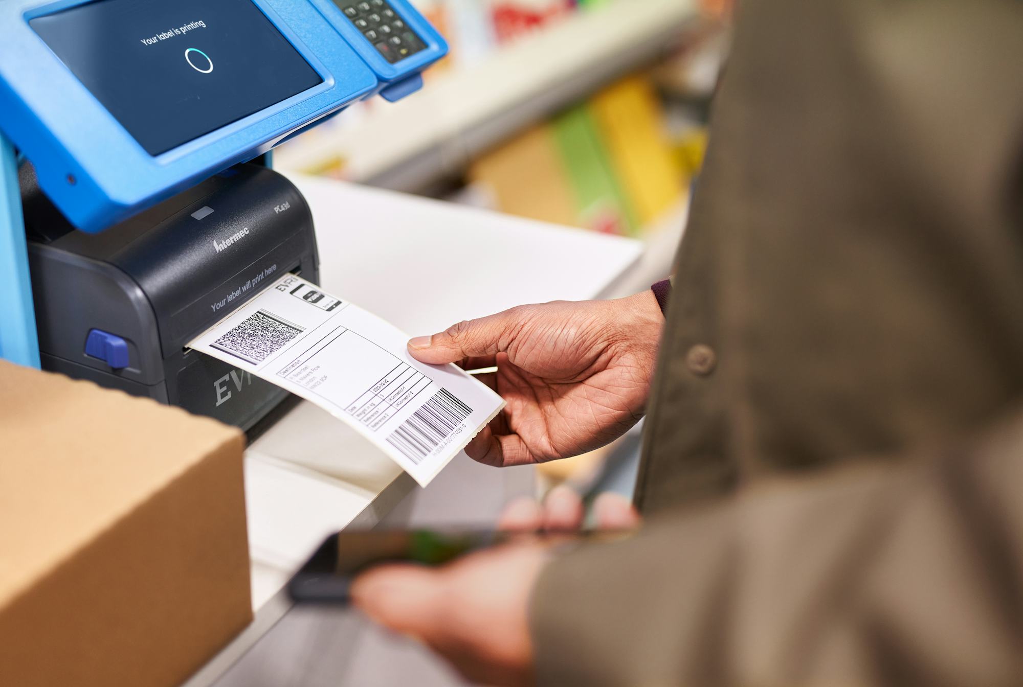 person collecting parcel label from blue printing machine