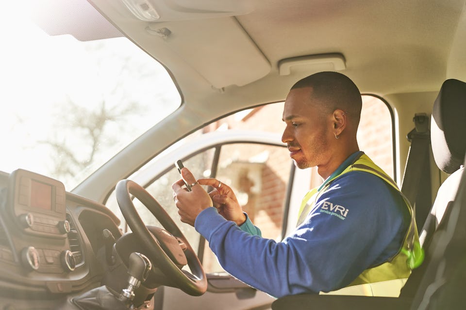 courier in van using smarthphone