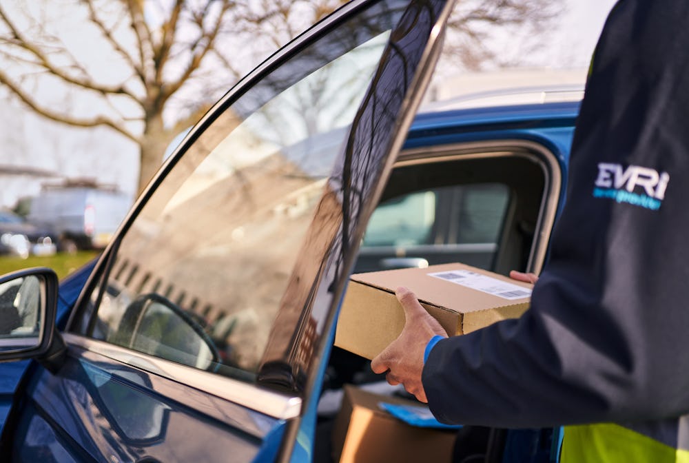 Photo of a courier opening door of blue car holding parcels