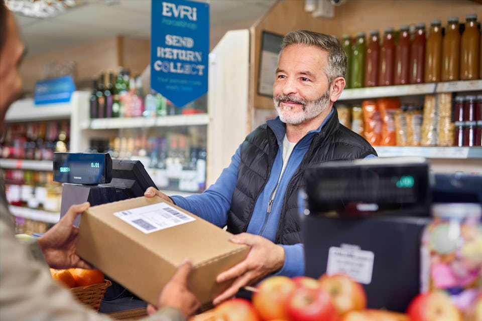 shopkeeper taking parcel from customer over counter