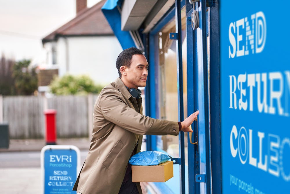 man carrying parcels approaching door to local shop