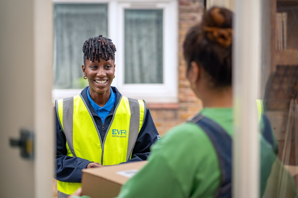 female courier stood at door greeting customer holding package