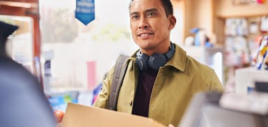 Photo of a customer holding parcel at shop counter