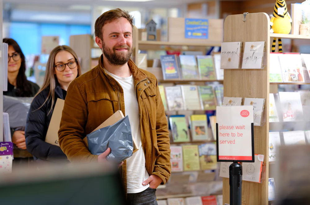 Man with parcel in the queue at a Post Office ParcelShop
