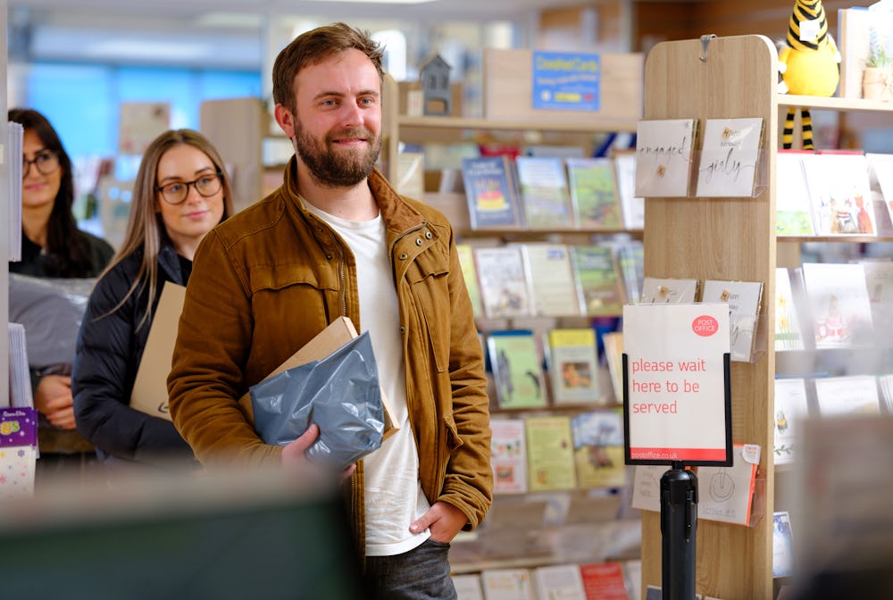 Man with parcel in the queue at a Post Office ParcelShop