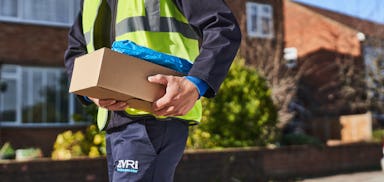 courier working down street holding parcel under arm