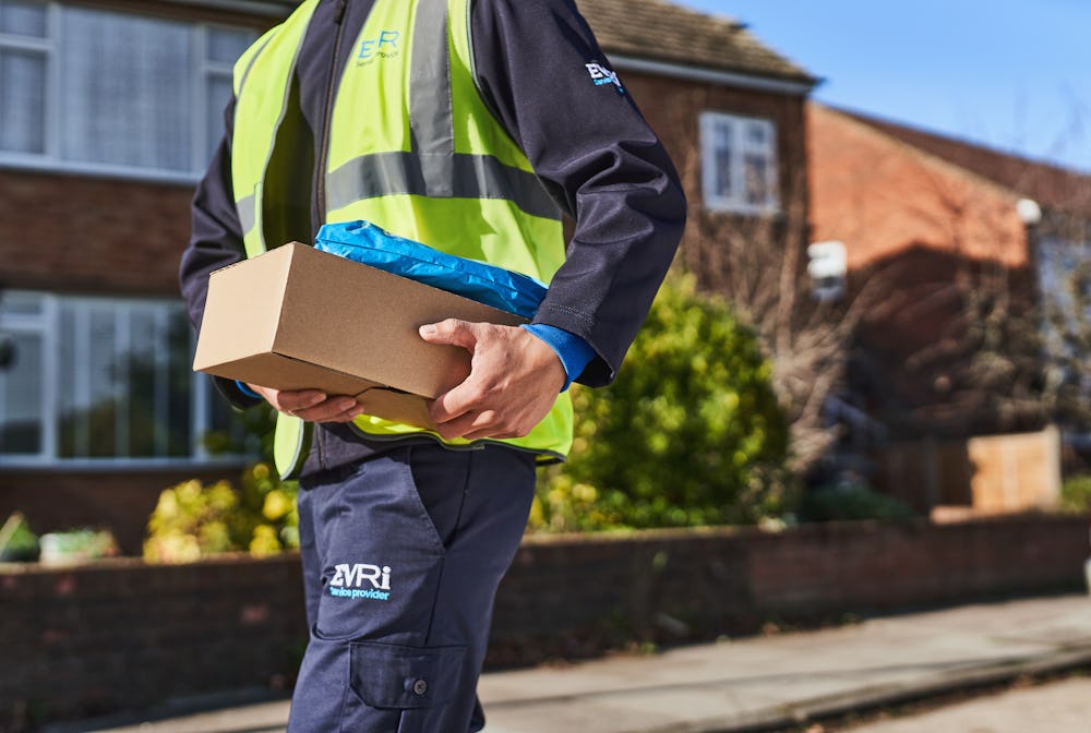 Photo of a courier working down street holding parcel under arm