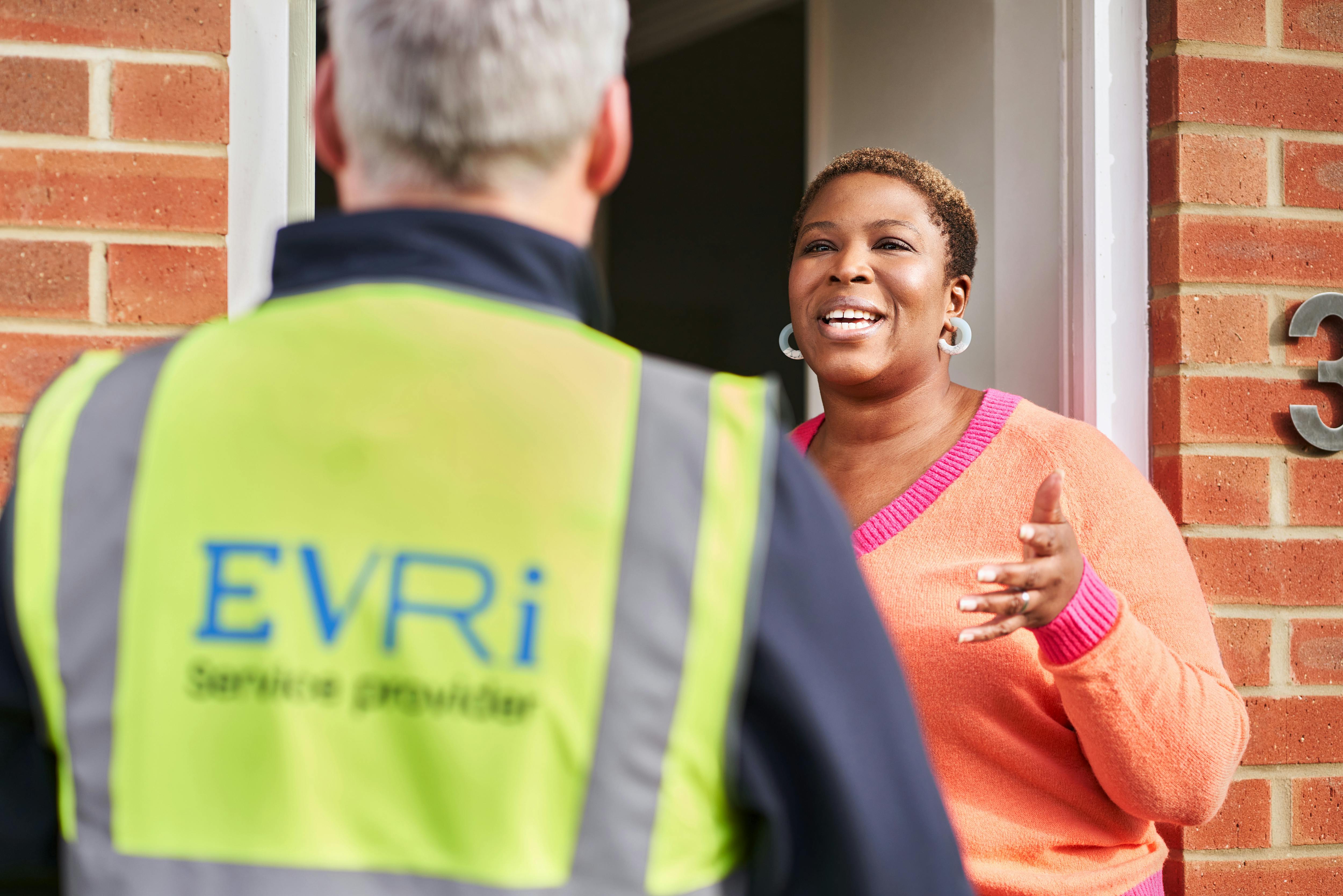 woman standing at her front door and talking to courier in high visibility vest