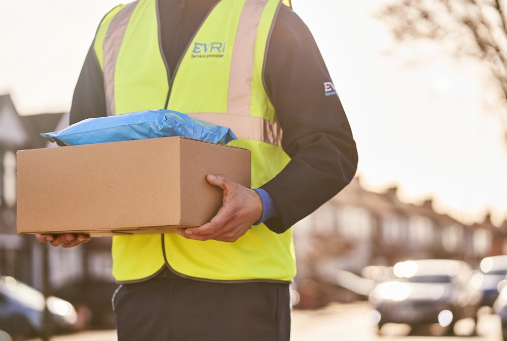 Photo of a courier holding parcels whole walking down street