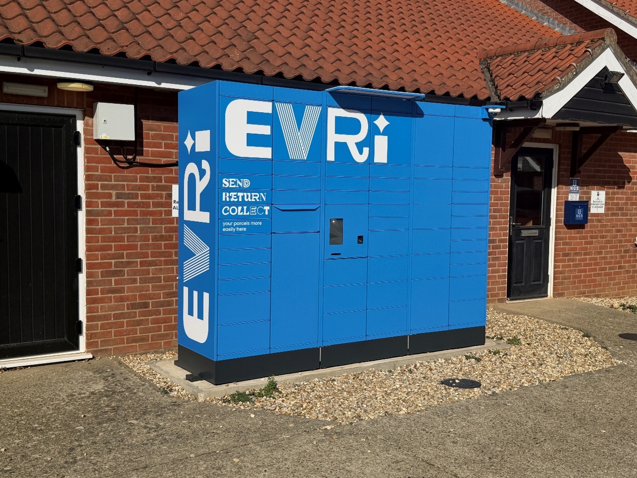 Blue Evri parcel locker outside a brick building at Dereham Town football club
