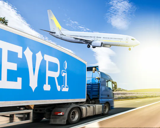 A side profile view shows an Evri branded lorry is driving along a straight road with an aeroplane that can be seen closely above.