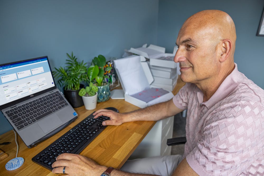 Business owner sat at a desk in their home office using their laptop to book multiple parcels