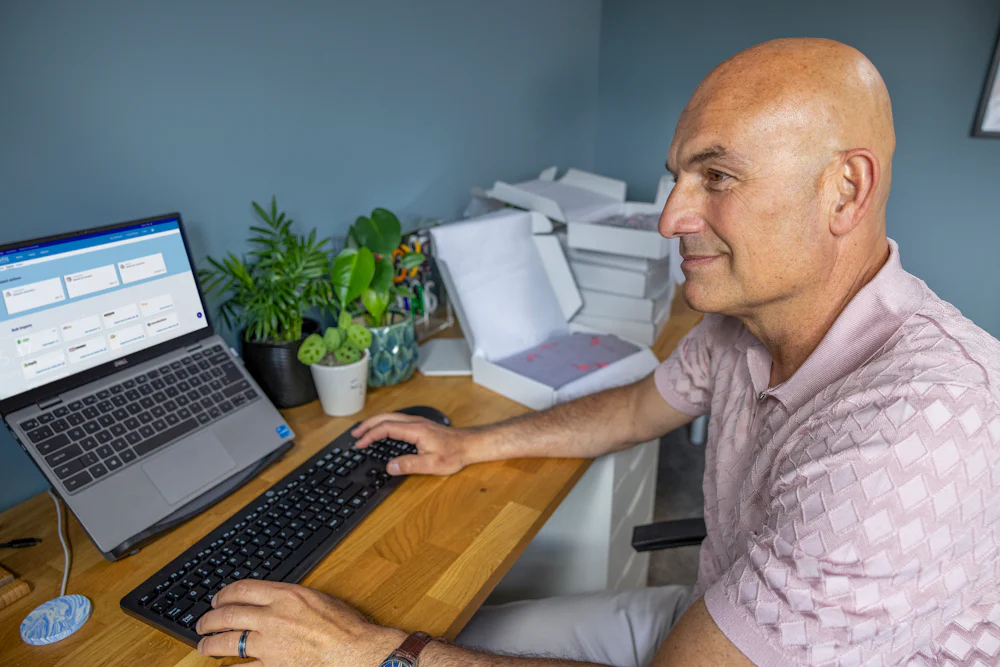 Business owner sat at a desk in their home office using their laptop to book multiple parcels