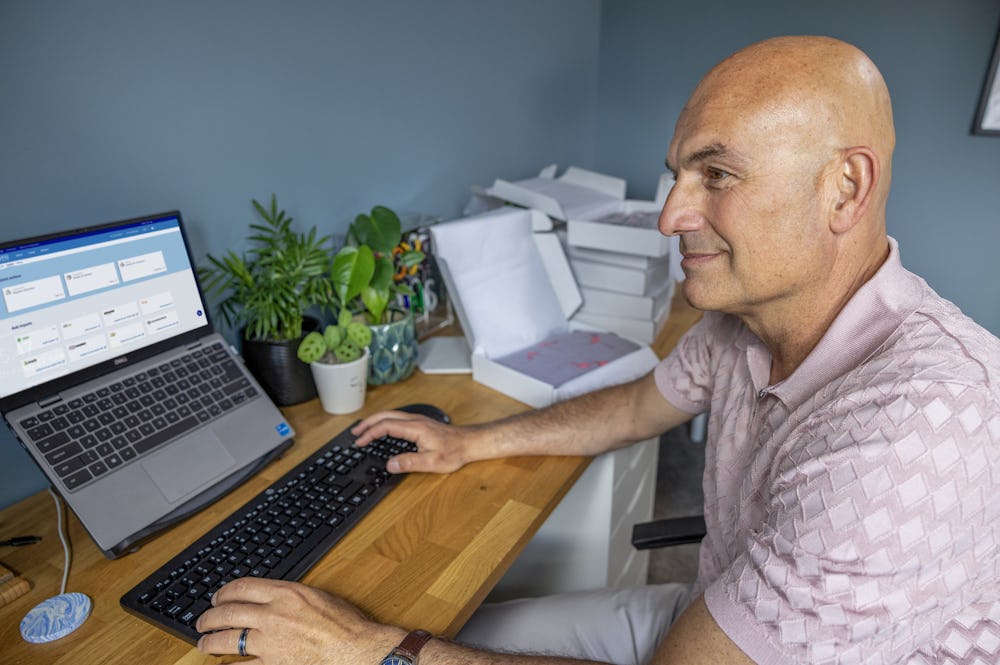 Business owner sat at a desk in their home office using their laptop to book multiple parcels