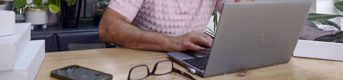 Customer sat at a desk in their office using a laptop with multiple parcels packaged next to them. Their hand is positioned against their head to show concentration.