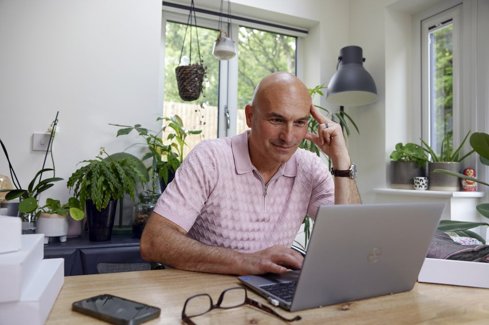 Customer sat at a desk in their office using a laptop with multiple parcels packaged next to them. Their hand is positioned against their head to show concentration.