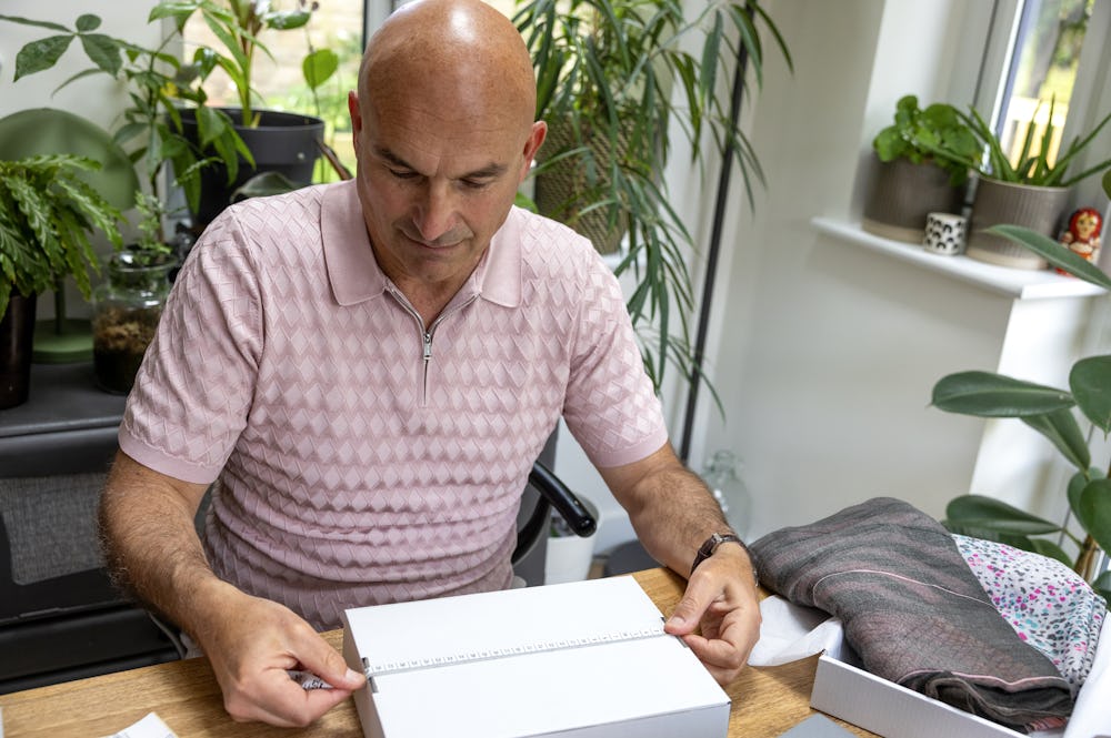 Customer sat at a desk holding a tape measure across their parcel to measure its size.