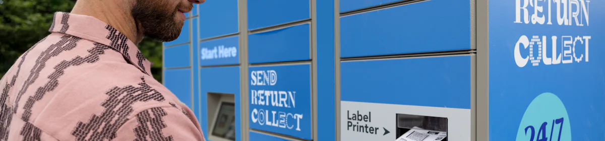 Customer holding parcel and standing outside at an Evri Locker, watching as their label prints out