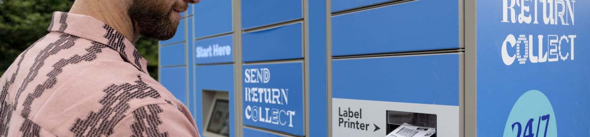 Customer holding parcel and standing outside at an Evri Locker, watching as their label prints out