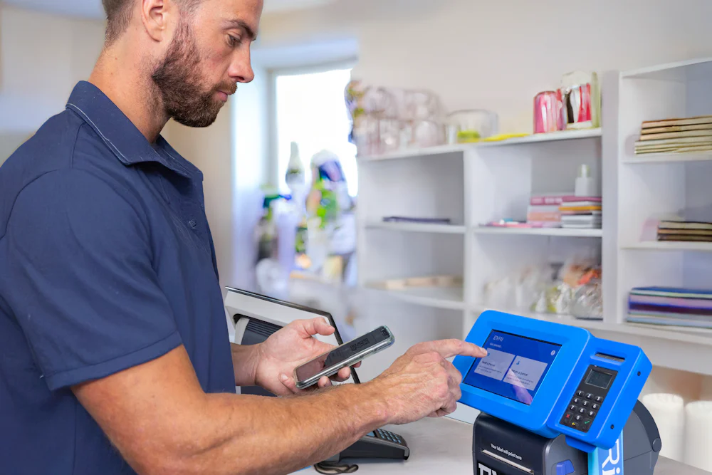 Customer in a ParcelShop store holding their mobile phone and entering information on a Print in Store device for printing their label.