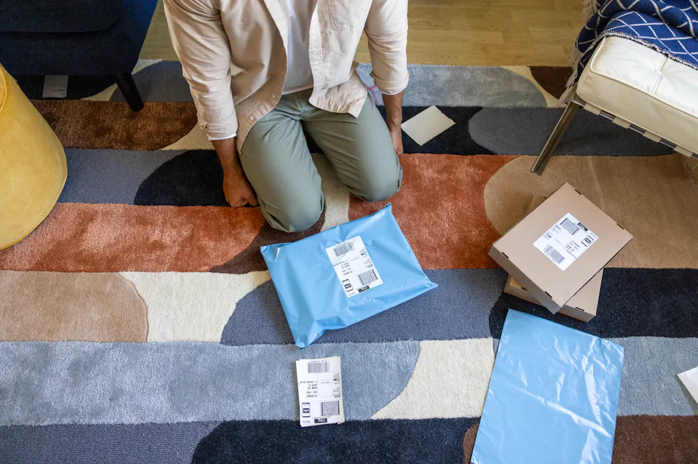 A customer is crouched on the floor of their apartment, surrounded by parcels.