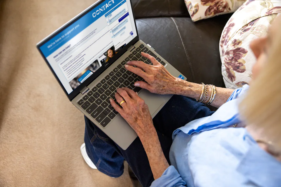 An older woman is navigating the Evri website. The help page is visible on her screen. The photo is taken from her perspective.