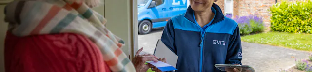 A courier is handing a blue collection receipt to an older woman at her door. Blue Evri van visible in the background.