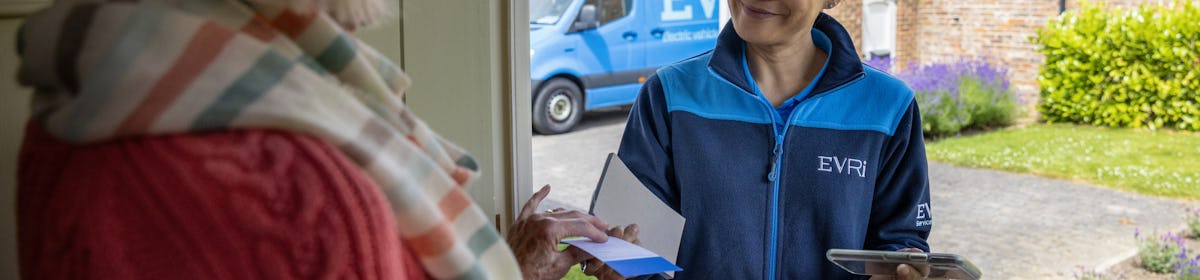 A courier is handing a blue collection receipt to an older woman at her door. Blue Evri van visible in the background.