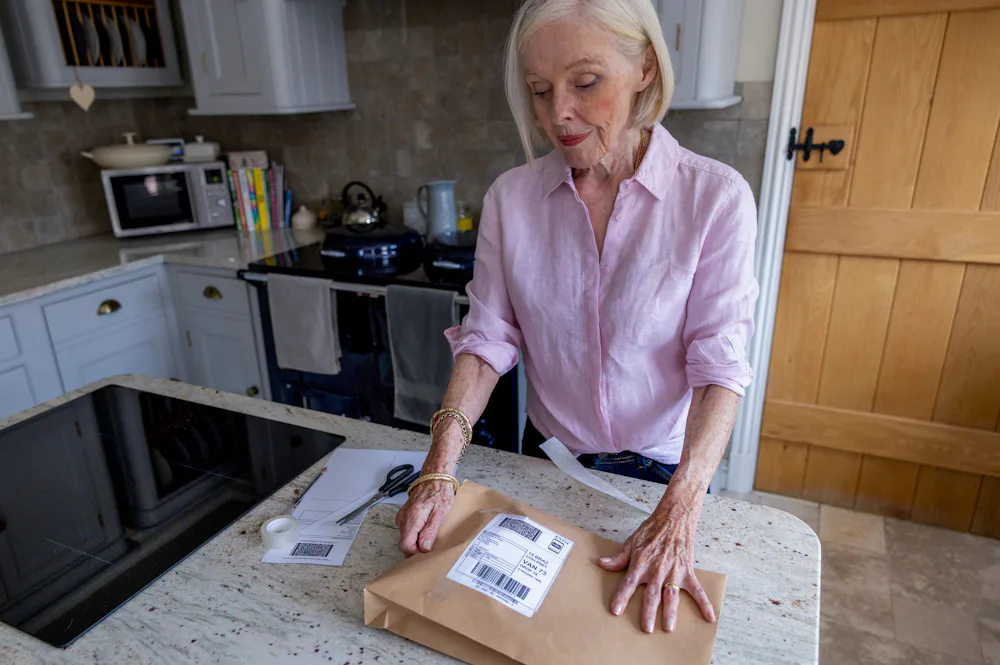 An older woman is wrapping a parcel. She is admiring the finished product.